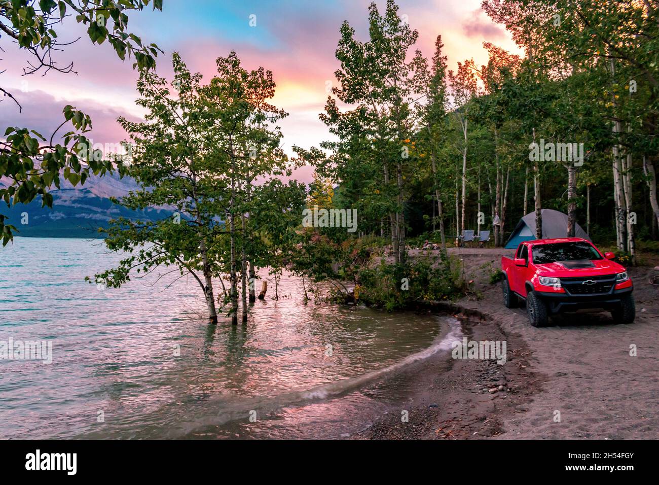 The Perfect Camping Spot On Abraham Lake With Trees Tent And Truck Infront Of Sunset Lit Sky